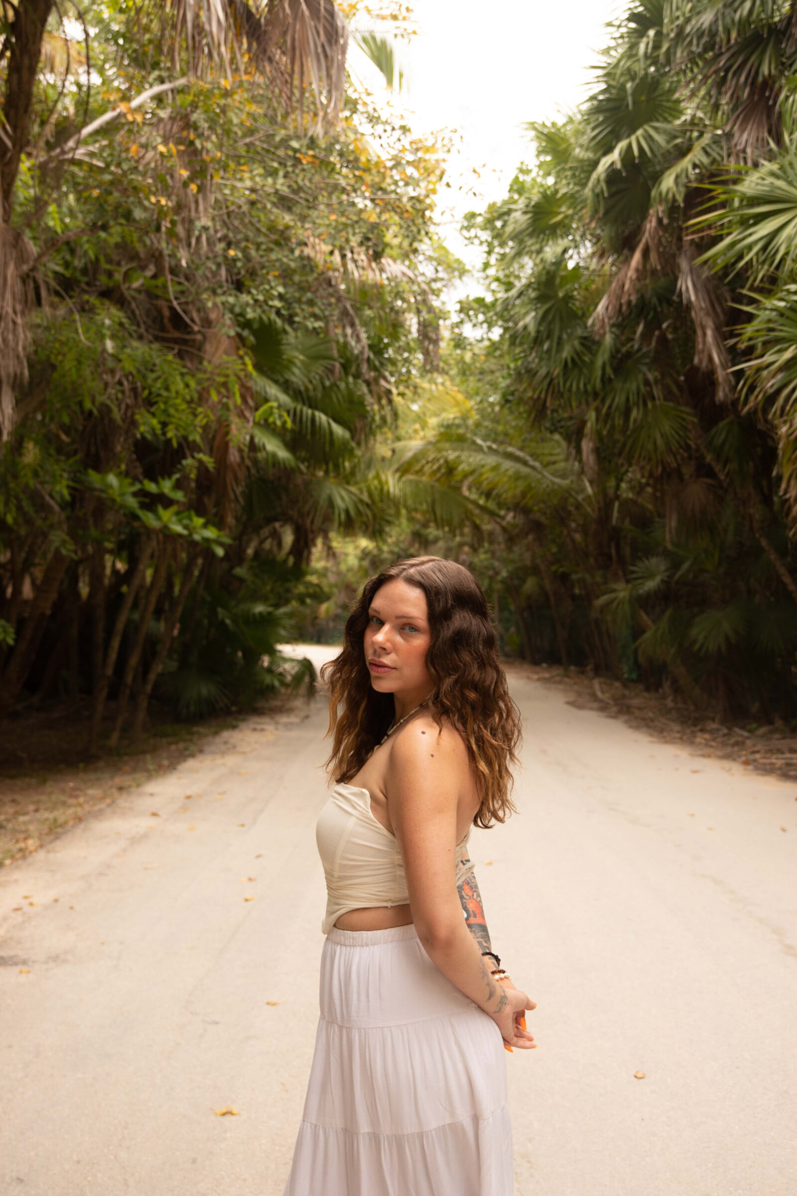 Mina walking through a tropical jungle path in Tulum